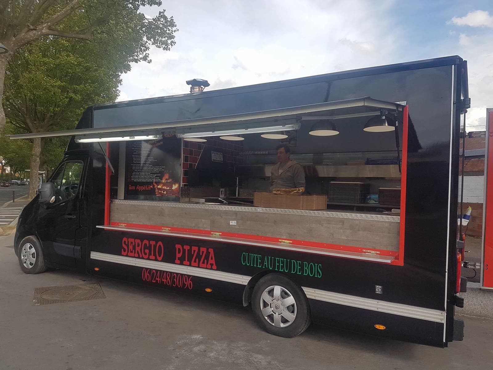 Le food truck ouvert, auvent levé, Sergio derrière le comptoir.