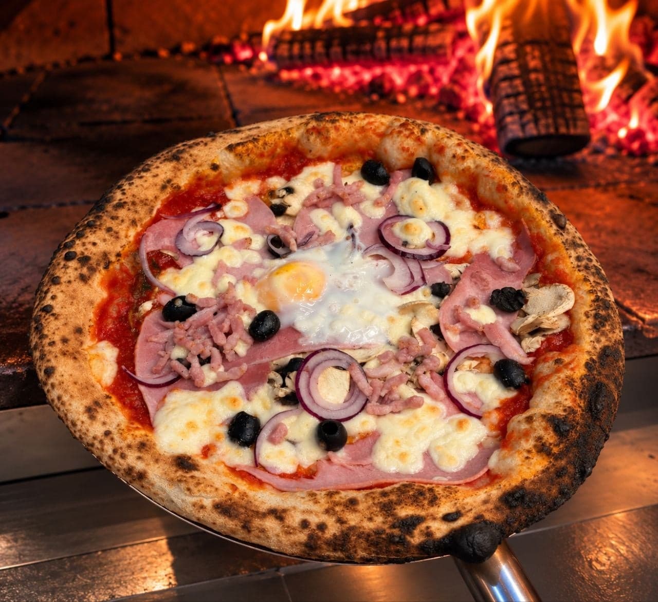 La pizza Fermière sur la pelle, devant les flammes du four à bois.