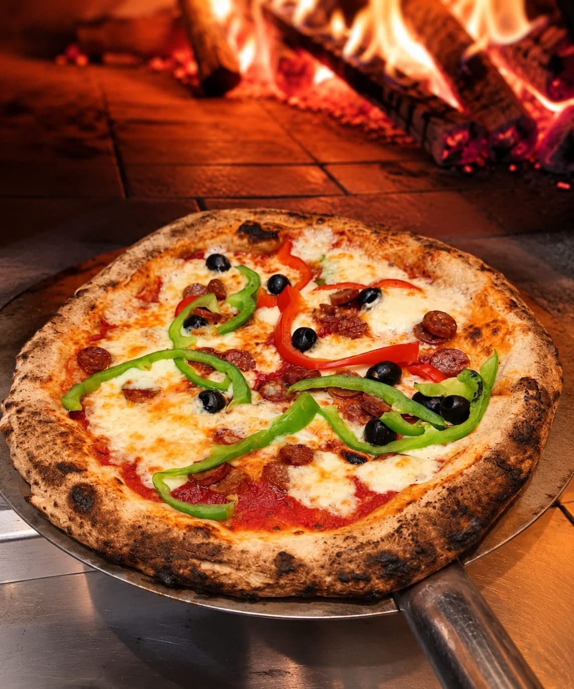 La pizza Orientale sur la pelle, devant les flammes du four à bois.