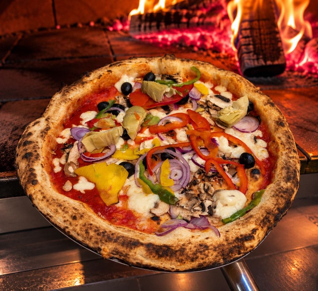 La pizza Végétarienne sur la pelle, devant les flammes du four à bois.